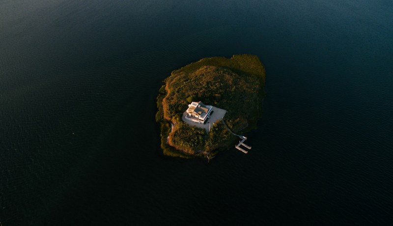 drone aerial view of a white house with a dock on a small green island at long beach island, the best neighbors 4k