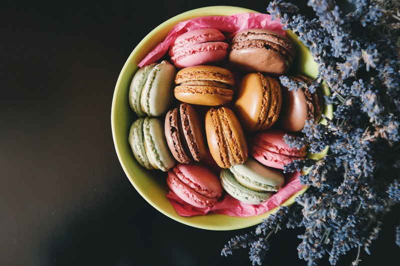 an overhead shot of colorful macaroons in a bowl next to a bunch of dark blue lavender flowers, macaroons and lavender 4k