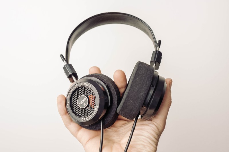 the grado headphones sr80e is held in a mans right hand, _grado headphones sr80e 4k
