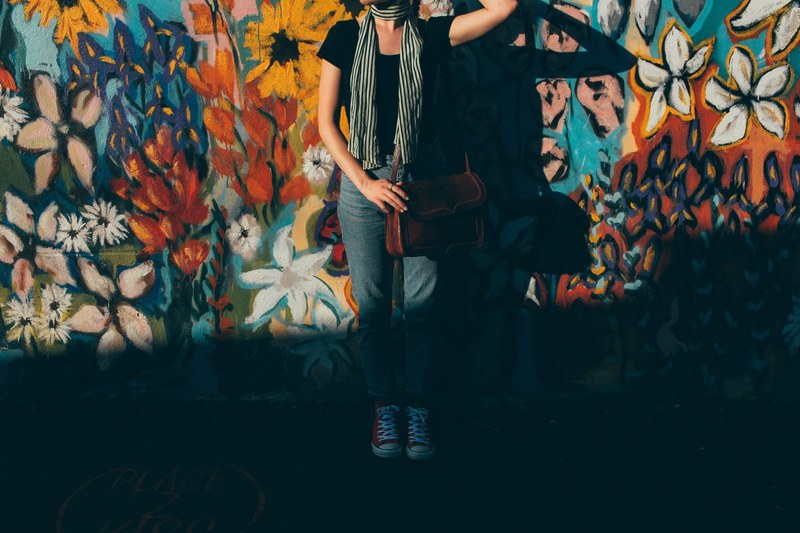 fashionable young woman in denim standing in front of colorful floral street art mural in nashville, flower child 4k