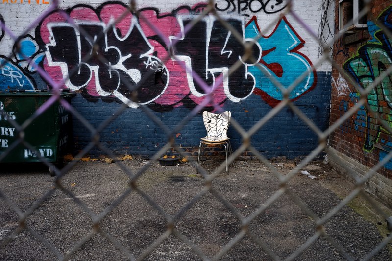 urban graffiti and an abandoned chair through a chainlink fence, one mans trash 4k