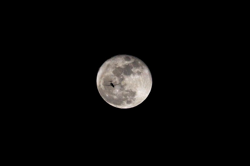 plane over atlanta silhouetted against the sky appears to fly across a lunar crater, fly me to the moon 4k