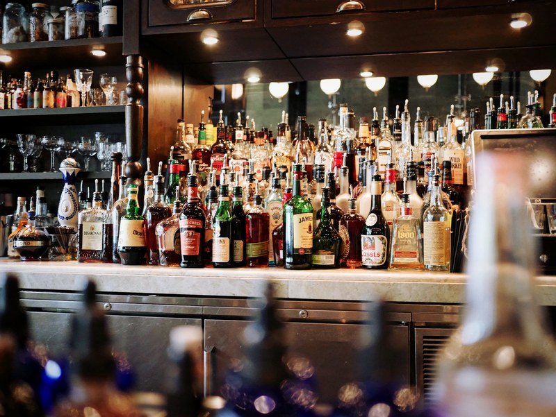 the interior view the counter of a bar with beer bottles in front of a mirror in weslodge, busy bar shelf 4k