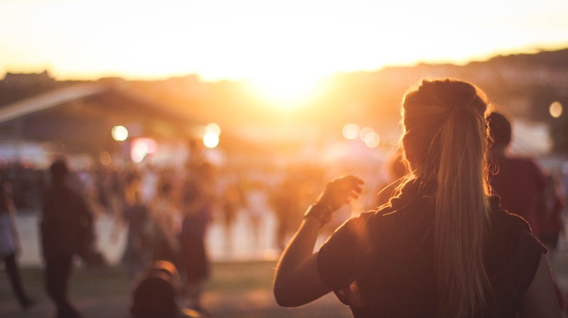 image of a blonde woman standing in a festival with lens flares in silhouette, woman standing in a festival 4k