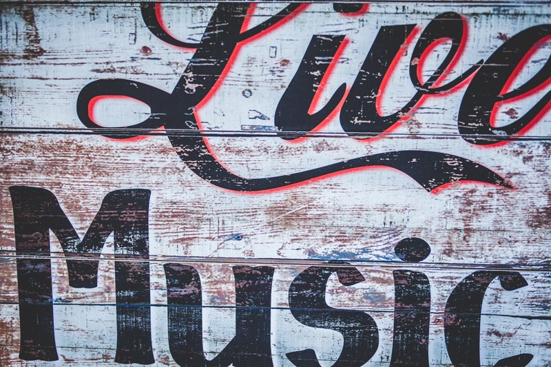 a graffiti sign on a worn out wooden wall reads live music, live music graffiti sign 4k