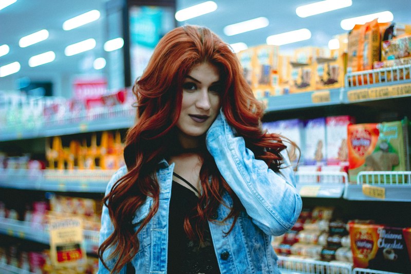 woman with long red hair poses in a grocery store candy aisle, glamorous grocery shopping 4k