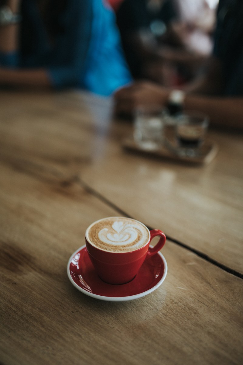 red latte coffee with foam artwork standing on wooden table in cafe, red latte with foam artwork 4k