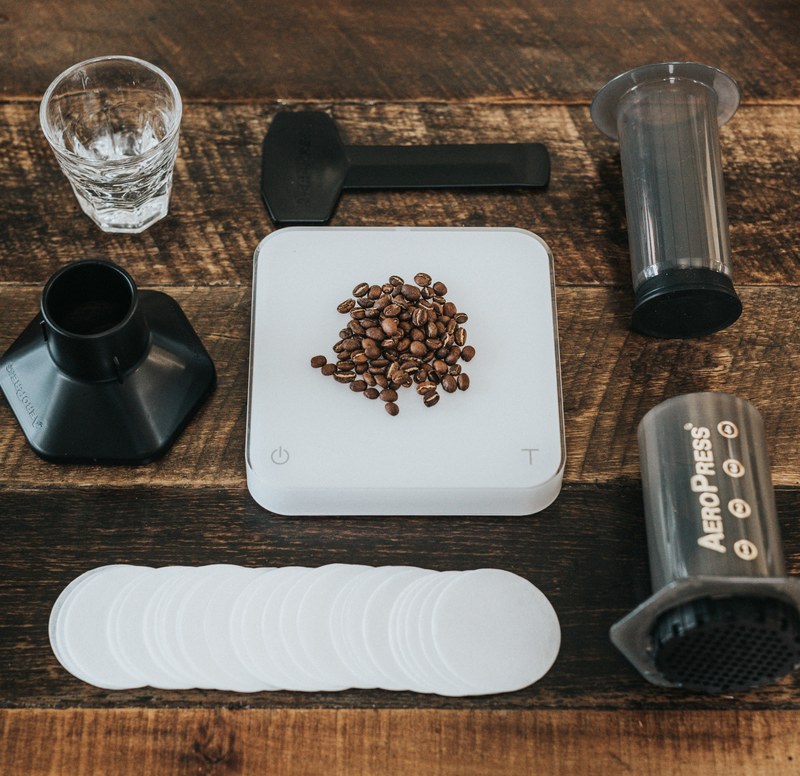 aeropress coffee press kit disassembled on a wooden table with coffee beans in the center, no right way to do it 4k