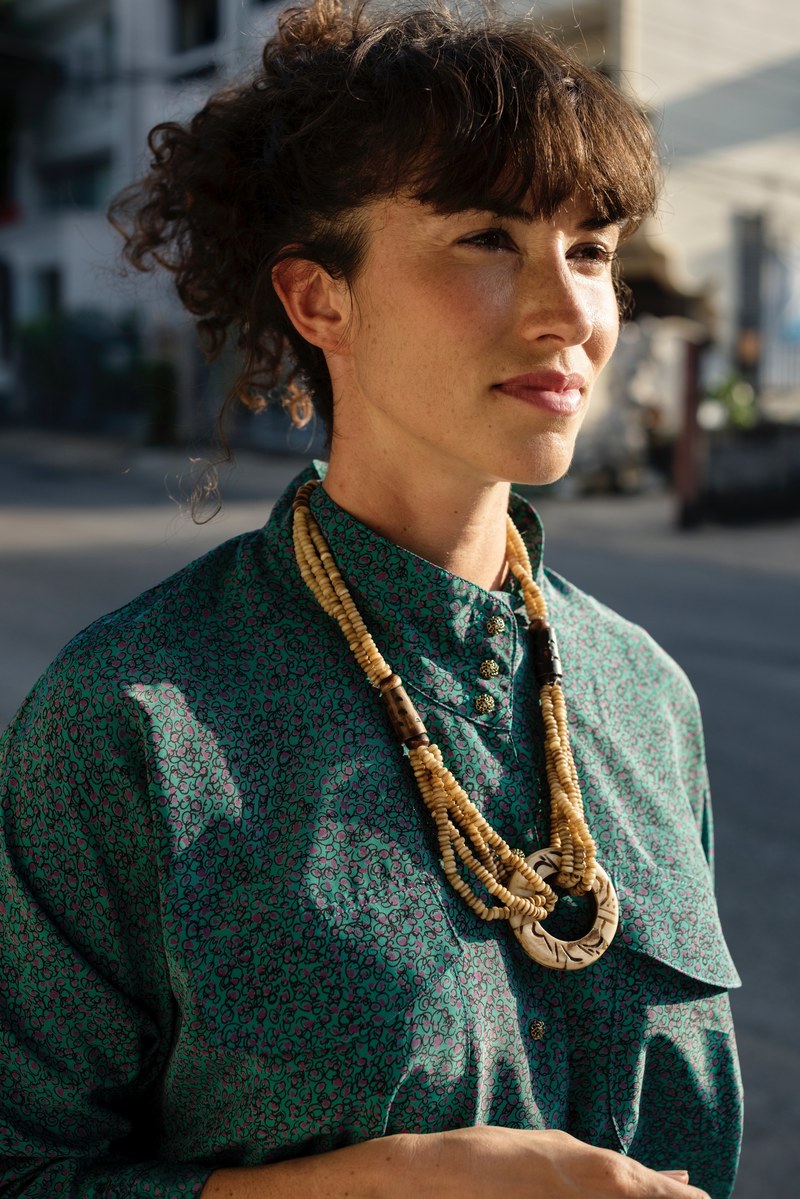 woman in bohemian chic clothing stands on a sunny city street, boho chic 4k