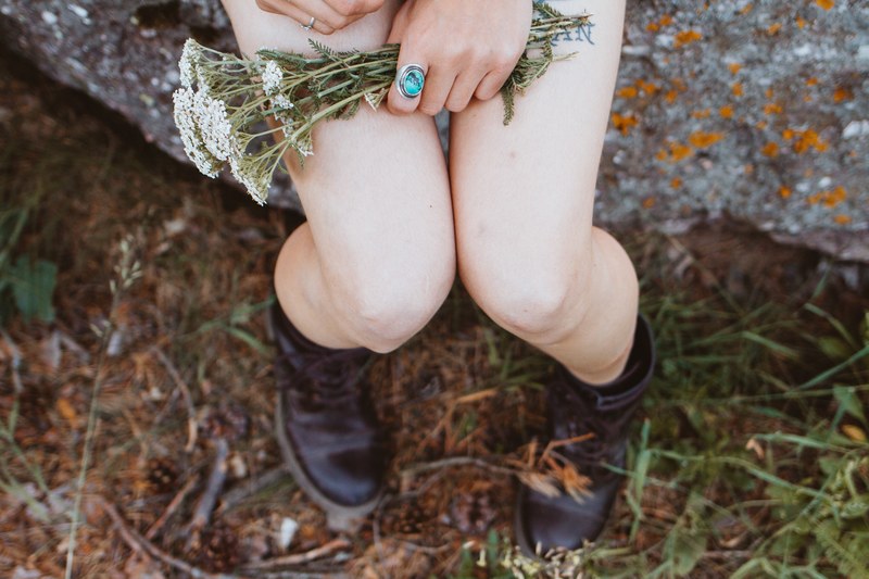 an overhead shot of a woman holding a bunch of tiny white flowers on her bare knees, bouquet on womans lap 4k