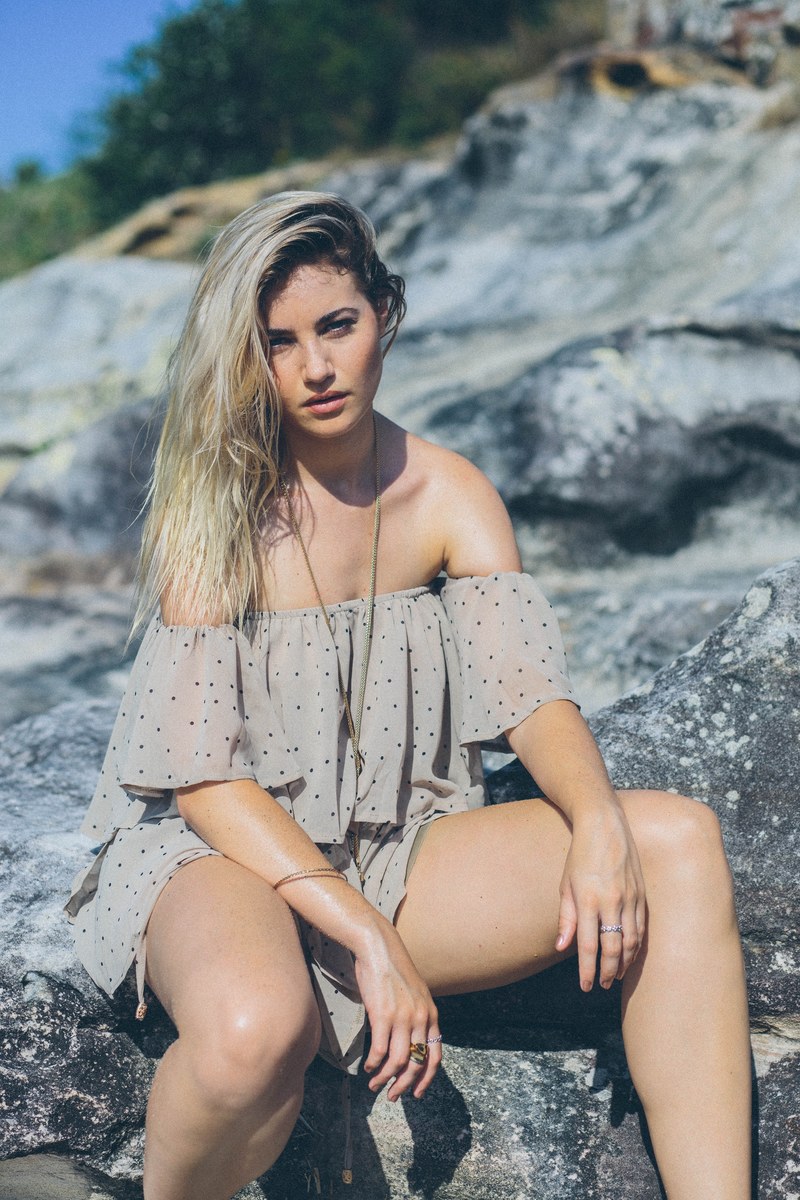 woman in a dress sitting on a rock and posing at cronulla beach, eyes that can see your heart 4k