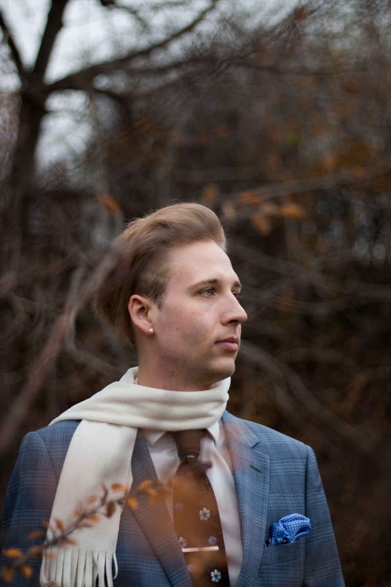 a man in a plaid suit tie and scarf among bare tree branches, elegant man in the autumn 4k