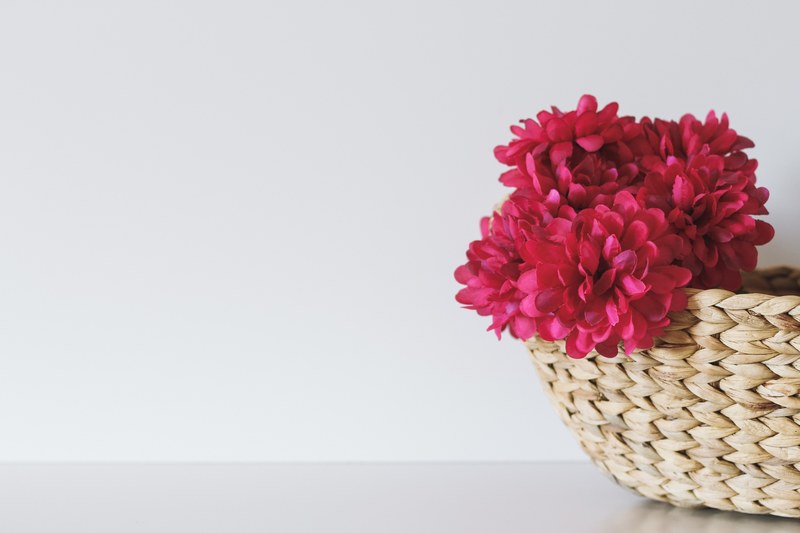red flowers in a wicker basket against a white background, minimal red flower basket 4k