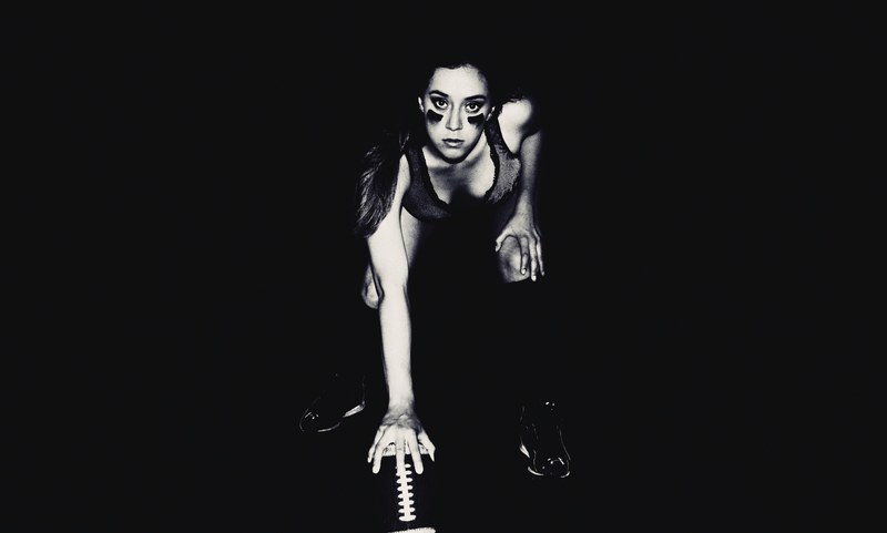 a woman with her face painted standing in a position to hike a football, woman football 4k