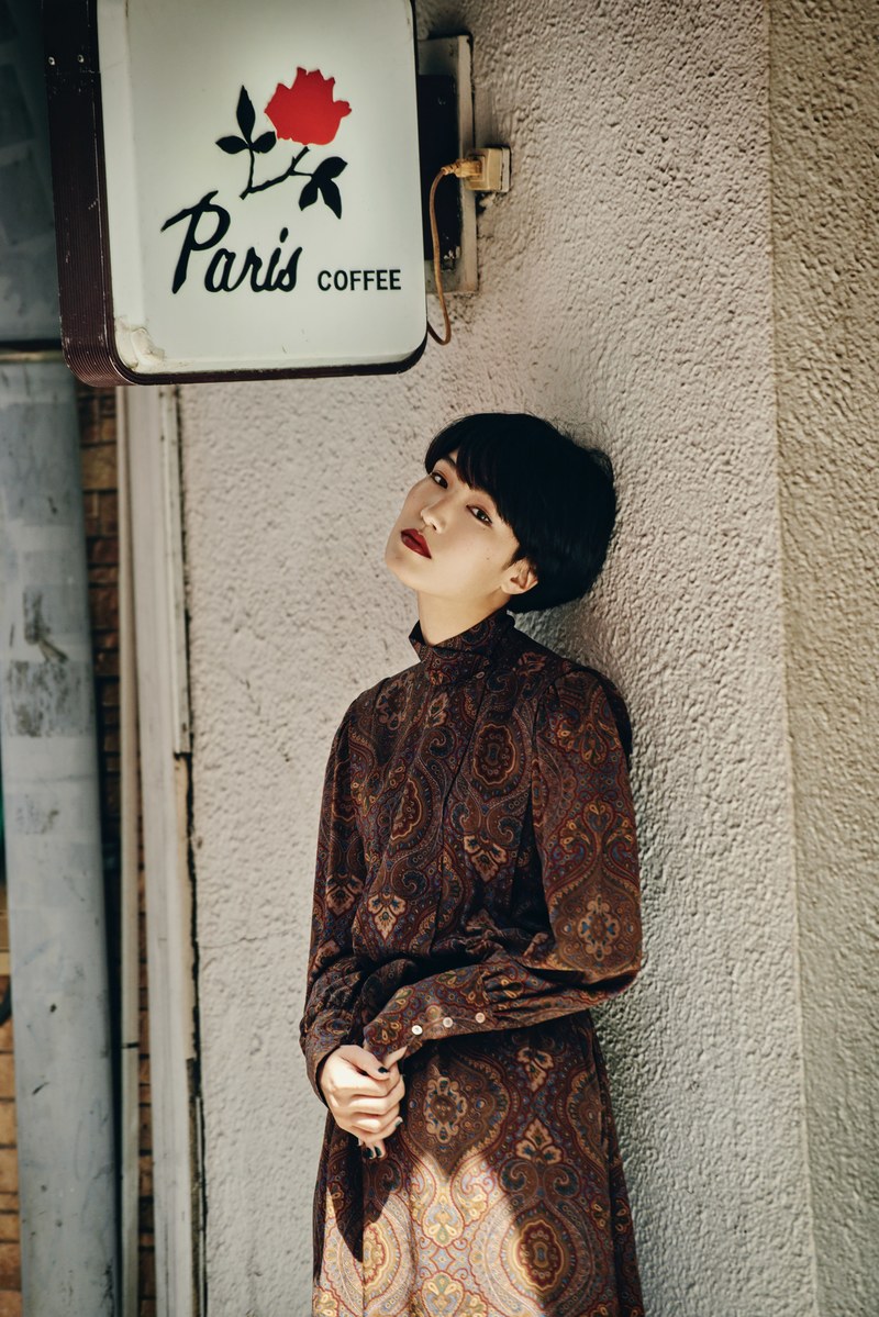trendy woman with an edgy haircut leaning against a wall, paris coffee 4k