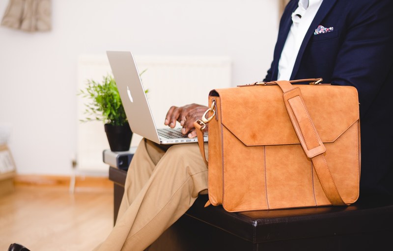 a man in a navy blue blazer typing on a macbook on his lap, businessman typing on a laptop 4k
