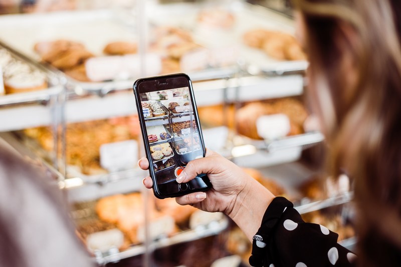 a person taking a photo of donuts at california donuts with their iphone cellphone, iphone bakery video 4k