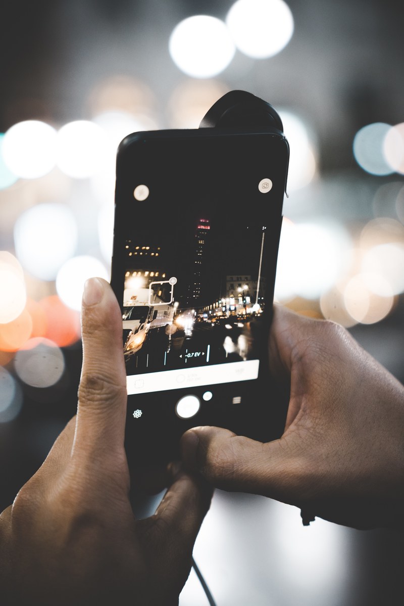 a person taking a picture of the city night life with their smartphone, _0001 4k