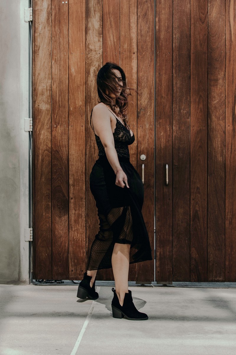woman in a dress with hair blown over her face in front of a wooden door, woman with hair over her face 4k