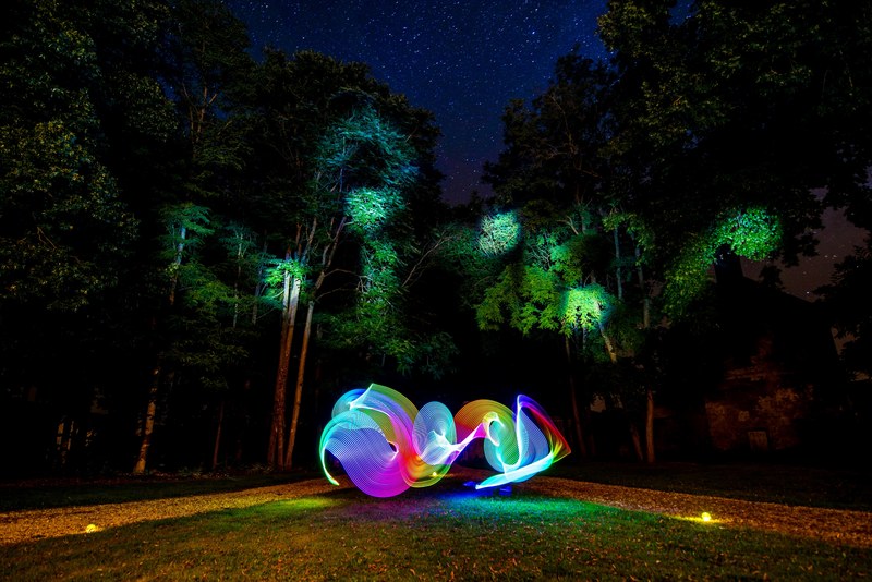 rainbow coloured led bright torch light trail on grass surrounded by trees, led light trail and trees 4k