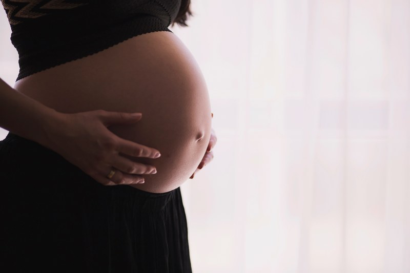pregnant woman in black holds her exposed stomach expectantly, expecting 4k
