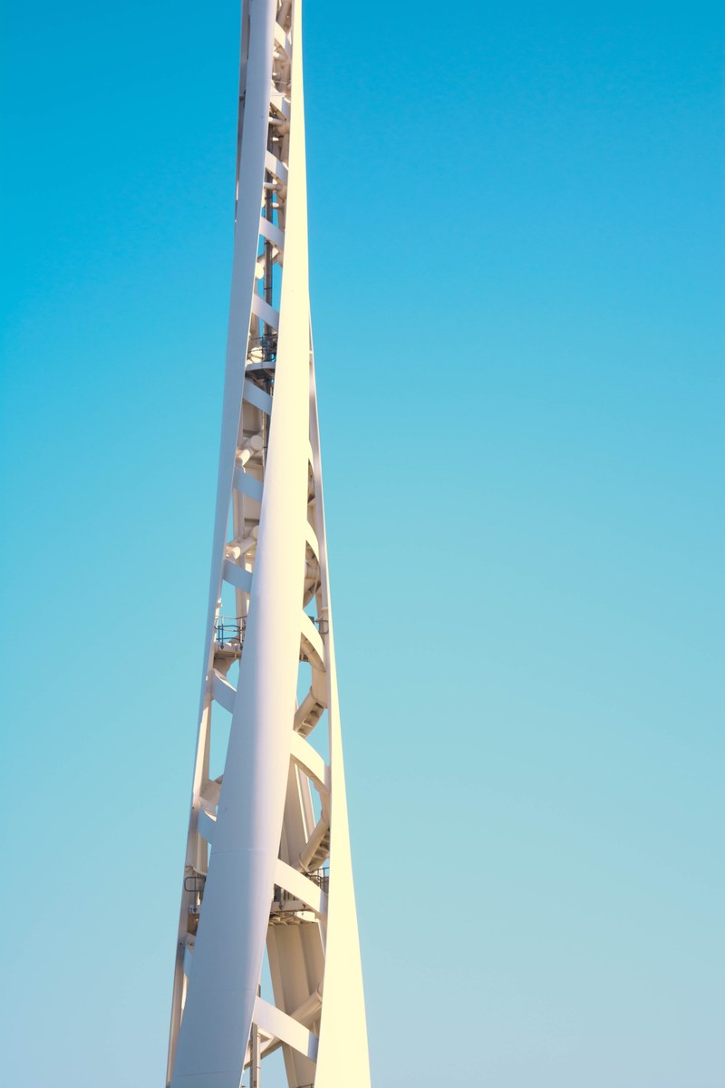 a tall twisting white structure against a blue sky, twisting steel structure 4k