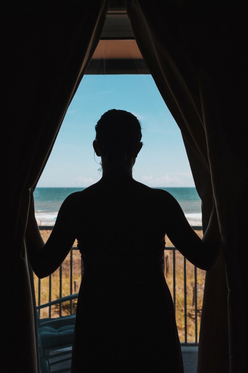 silhouette of the person looking through balcony curtains on the ocean isle beach coast, relief 4k