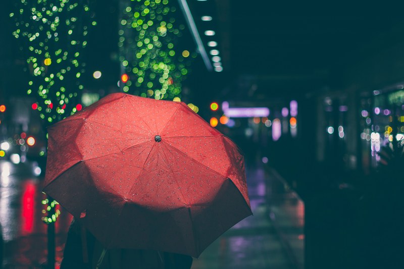 person carries a red umbrella on a rainy night in the city, walking alone in the rain 4k