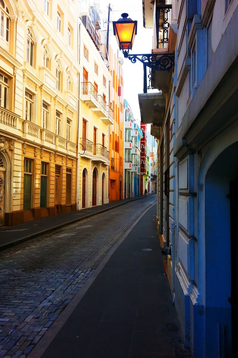 alleyway with colorful bright buildings flanking the road with a lit lamp protruding from a house, colorful alleyway 4k