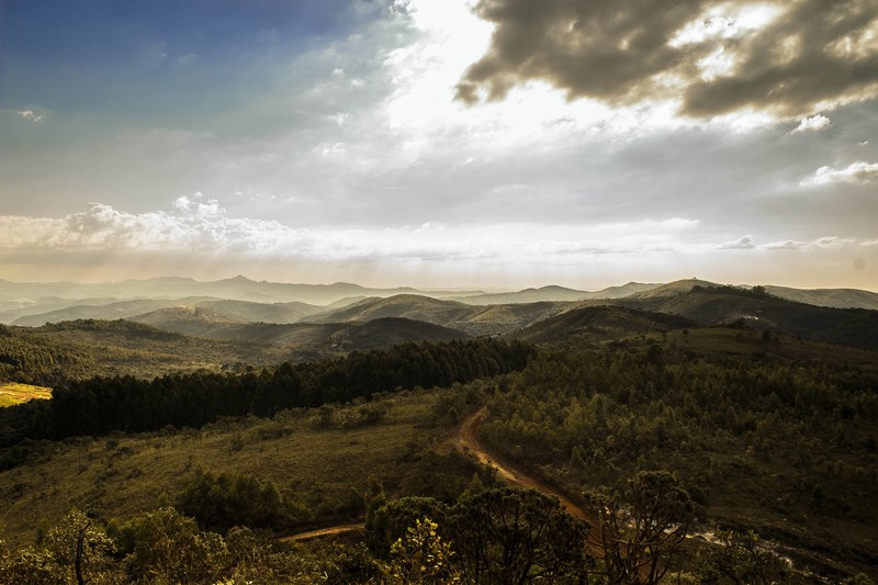 a picturesque hilly landscape covered with green vegetation with sun shining through the clouds, sun over the green hills 4k