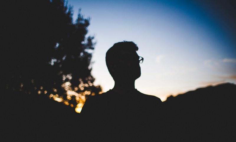 silhouette person in the darkness of sunrise or sunset wearing glasses somewhere in spain, silhouette man head wearing glasses 4k