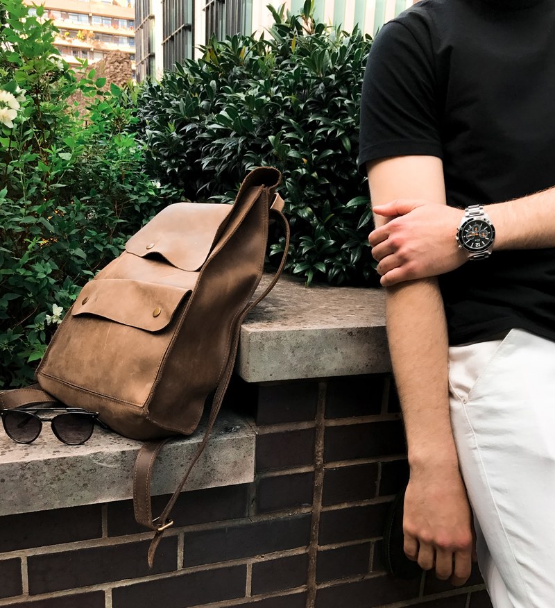 low shot of a trendy backpack sunglasses and a person wearing a watch, urban style 4k