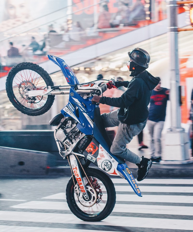 person with helmet in times square doing a trick on a motorcycle, trick motocycle times square 4k