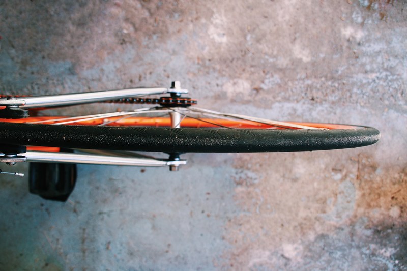 overhead view of bicycle tire with spokes and orange rim on top of concrete, bicycle tire on concrete 4k