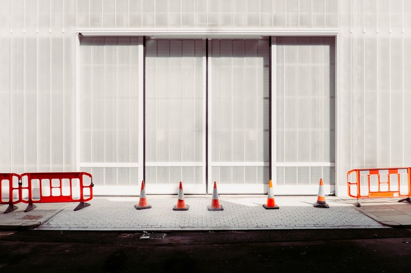 london sidewalk with orange construction cones and guard rails in front of a gray building, london sidewalk construction 4k