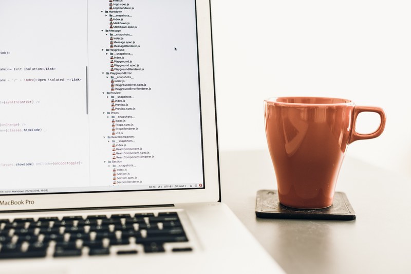 a brown mug next to a macbook with lines of code on its screen, developers mug 4k