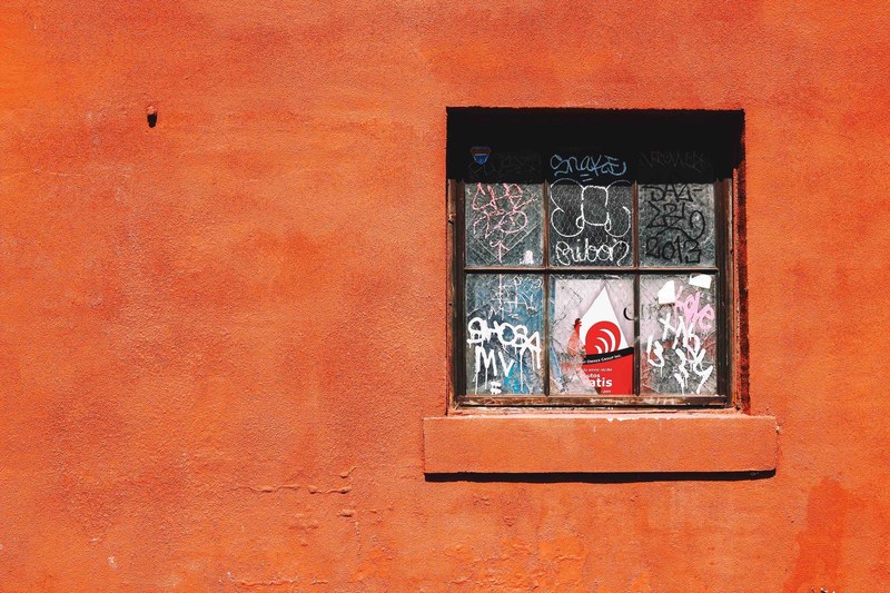 graffiti on a broken old window in a red painted building, orange broken window graffiti 4k