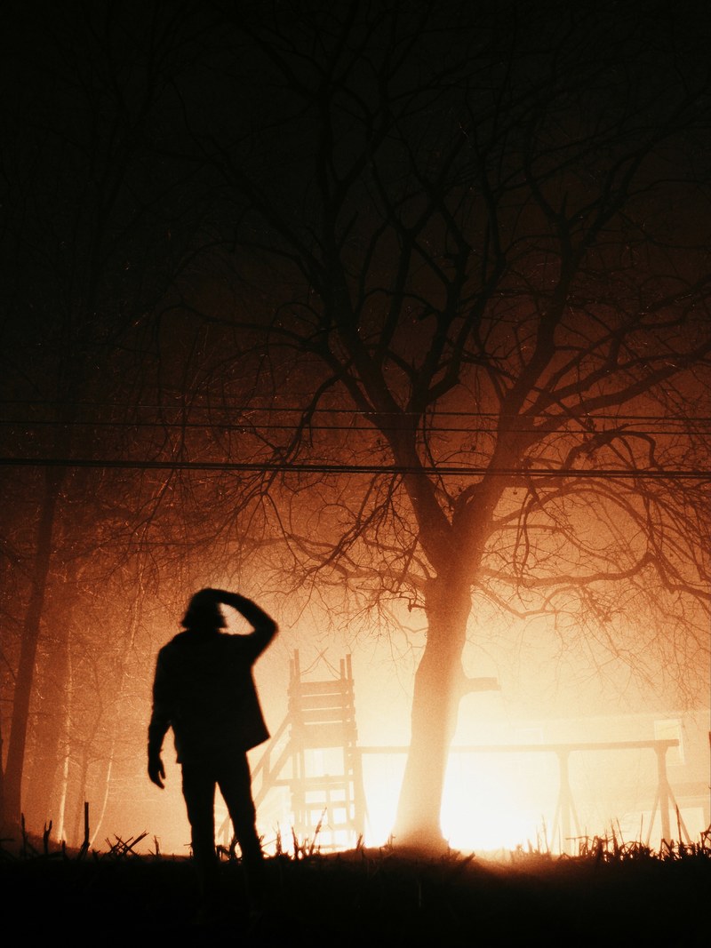 a night time shot of a silhouette man standing in front of a bright orange backdrop, anomaly 4k