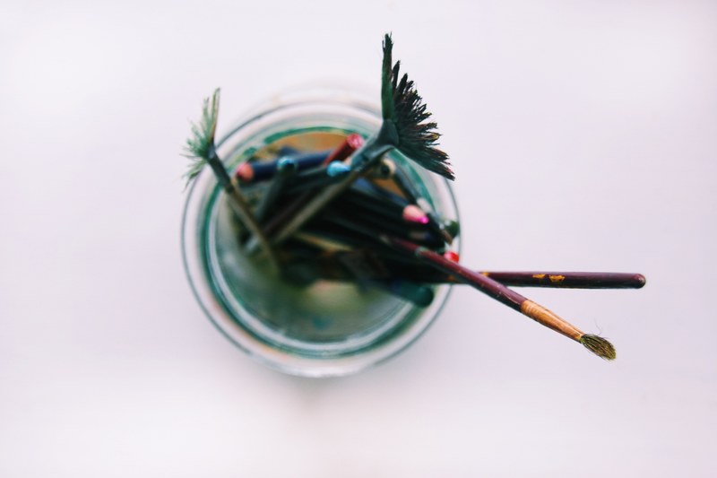 overhead shot of dirty paint brushes in a glass on a counter, jar of paint brushes 4k