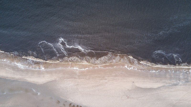 drone aerial view of the ocean washing on the sand beach at scheveningen, sea washing ashore drone view 4k