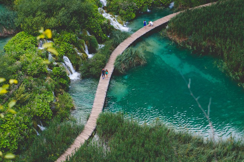 several people on a walkway over a pond in croatia, green pond walkway 4k