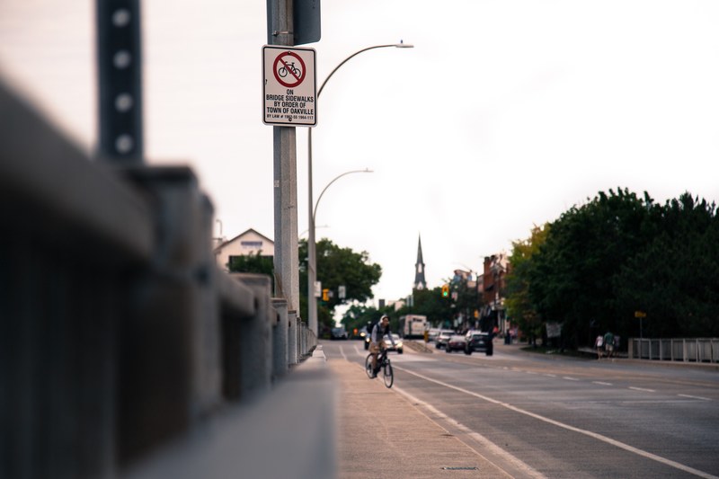 man on bike riding down sidewalk next to road with cars in the background, man on bike on road 4k