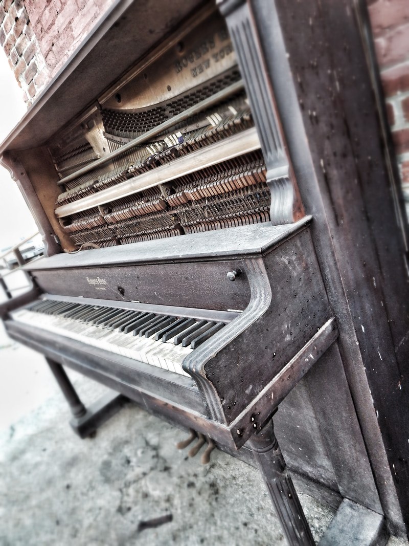 an antique wooden piano by a brick wall in west bottoms, _piano 4k