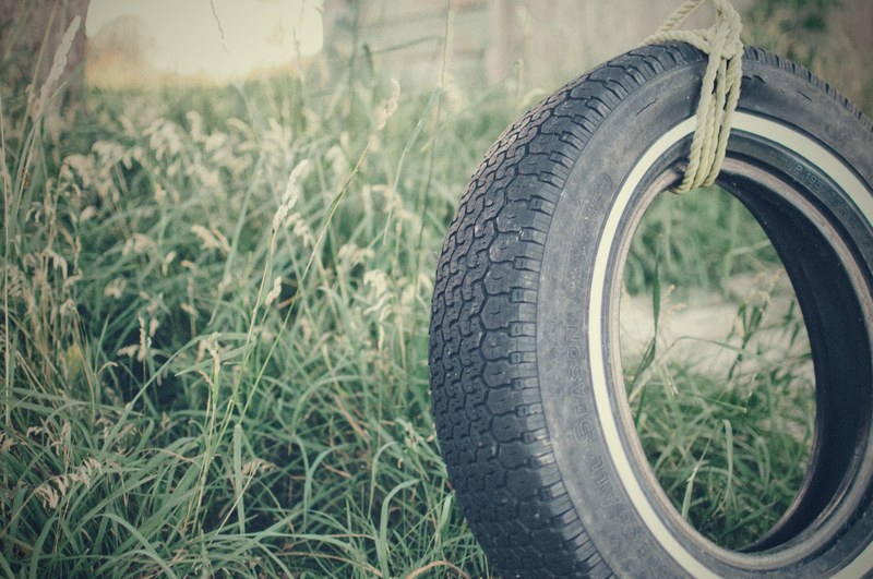 swinging car wheel tyre on rope in grass field, swing tyre in field 4k