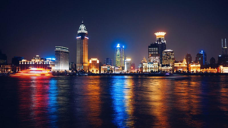 a nighttime bay view facade of a downtown district in a metropolitan area by the sea beautified by colorful rays of light, downtown with rays of light 4k