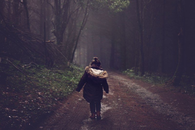 a girl wearing boots and a dark coat looks at the ground while she walks along a path in wye valley spa, a little girl walking along a path_ 4k