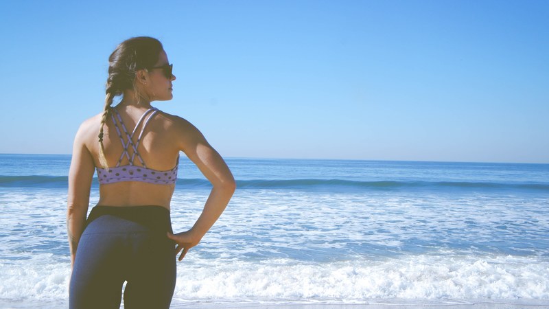 a woman wearing leggings a sports bra and sunglasses with a braid in her hair in manhattan beach, manhattan beach woman 4k