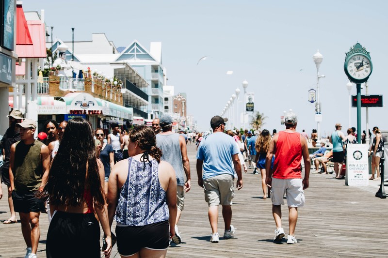 diverse crowd of tourists walk along a pier in ocean city, vacation 4k