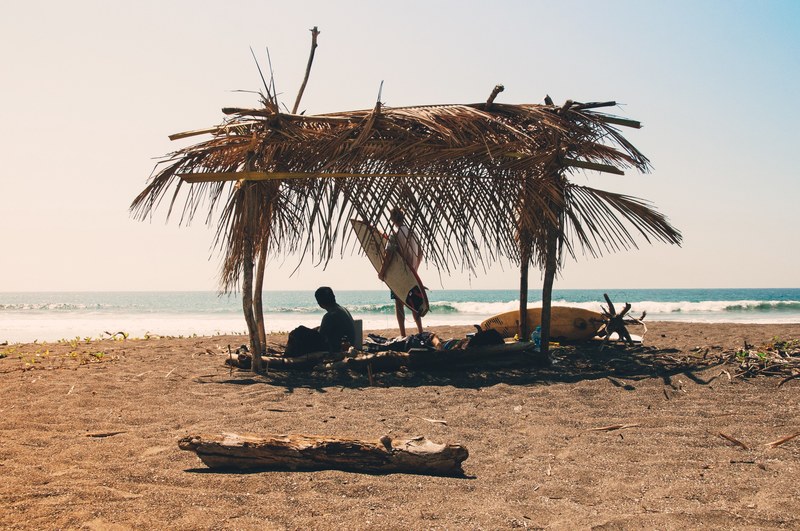 surfers under a tropical surf shack on a sand beach in guanacaste province, room with a view 4k
