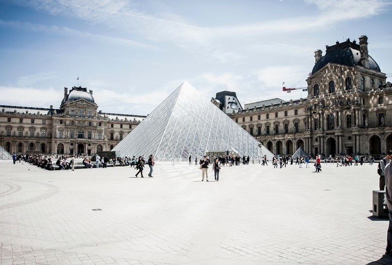 groups of people walking in front of the glass pyramid in the louvre courtyard in paris, louvre courtyard with visitors 4k